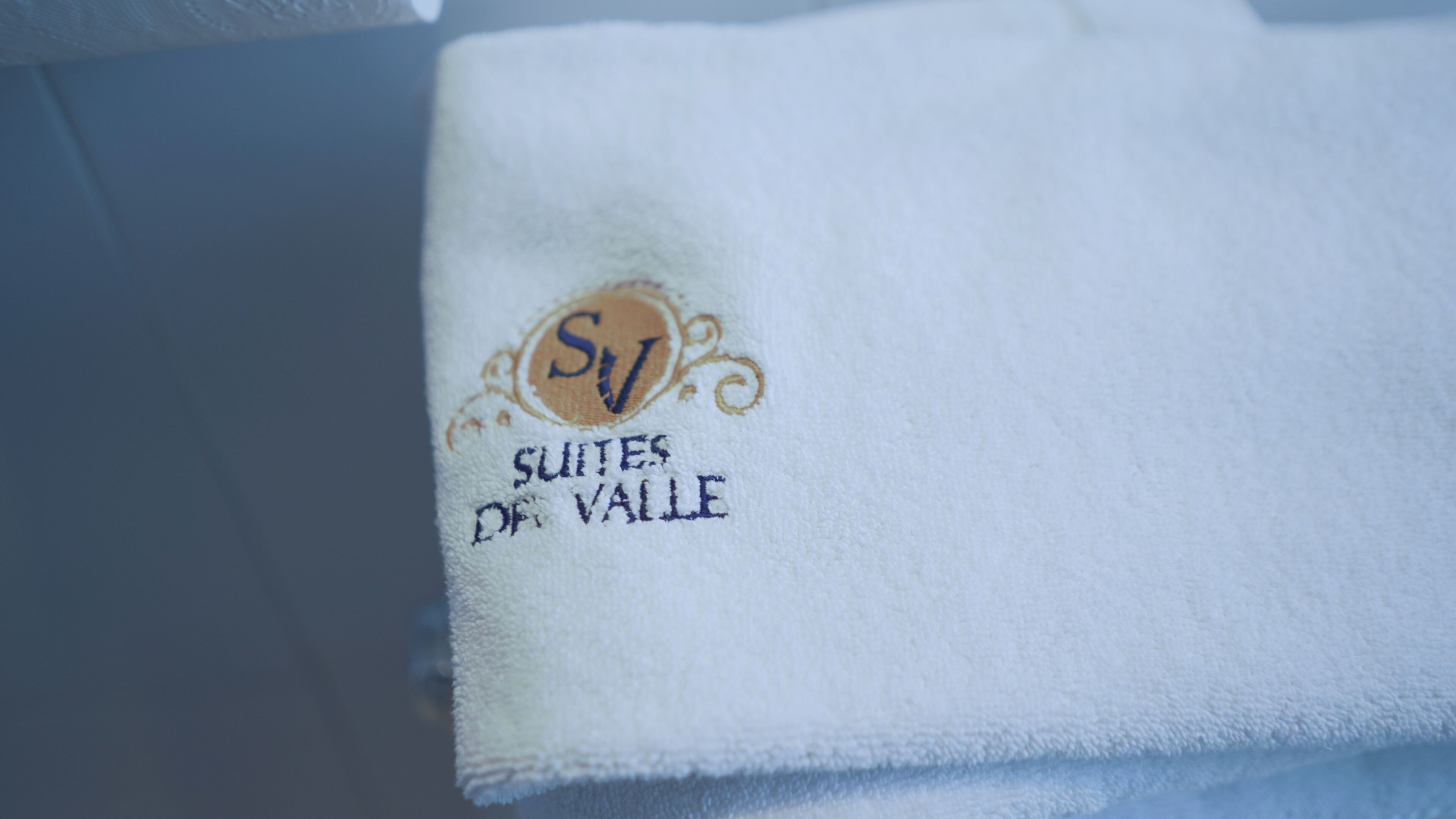 A white towel with embroidered text "SUITES OF VALE" and a logo.