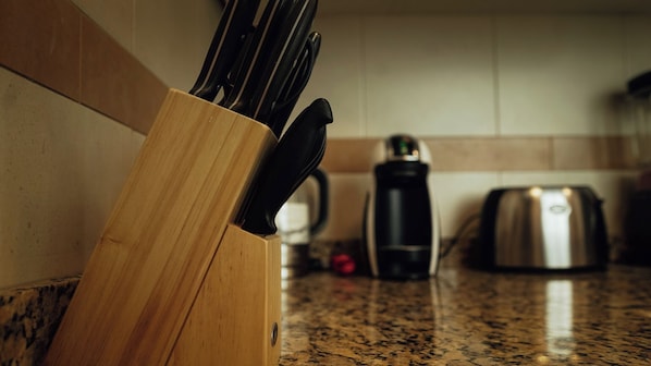 Una encimera de cocina con un bloque de cuchillos, una cafetera y un tostador.
