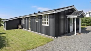 En enplansbyggnad med en mörk fasad, vita detaljer och flera fönster.