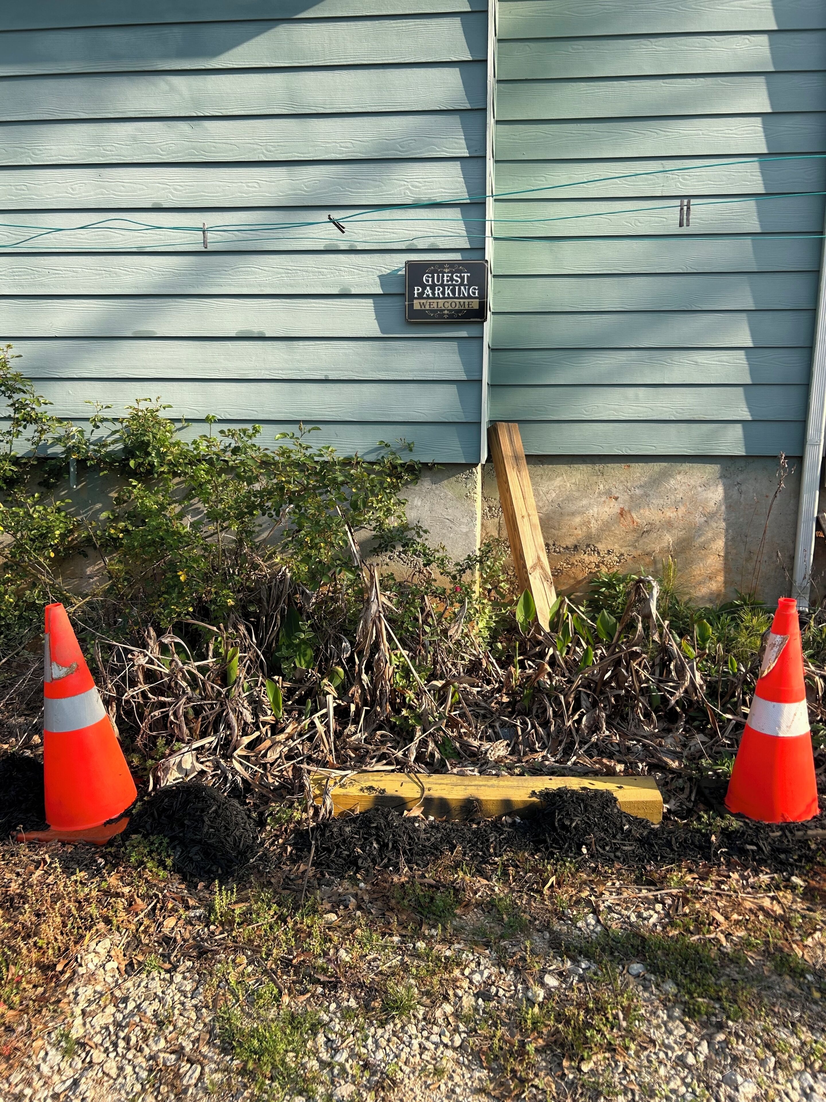 Área de estacionamento para hóspedes, com placa, dois cones de trânsito e um poste de madeira.
