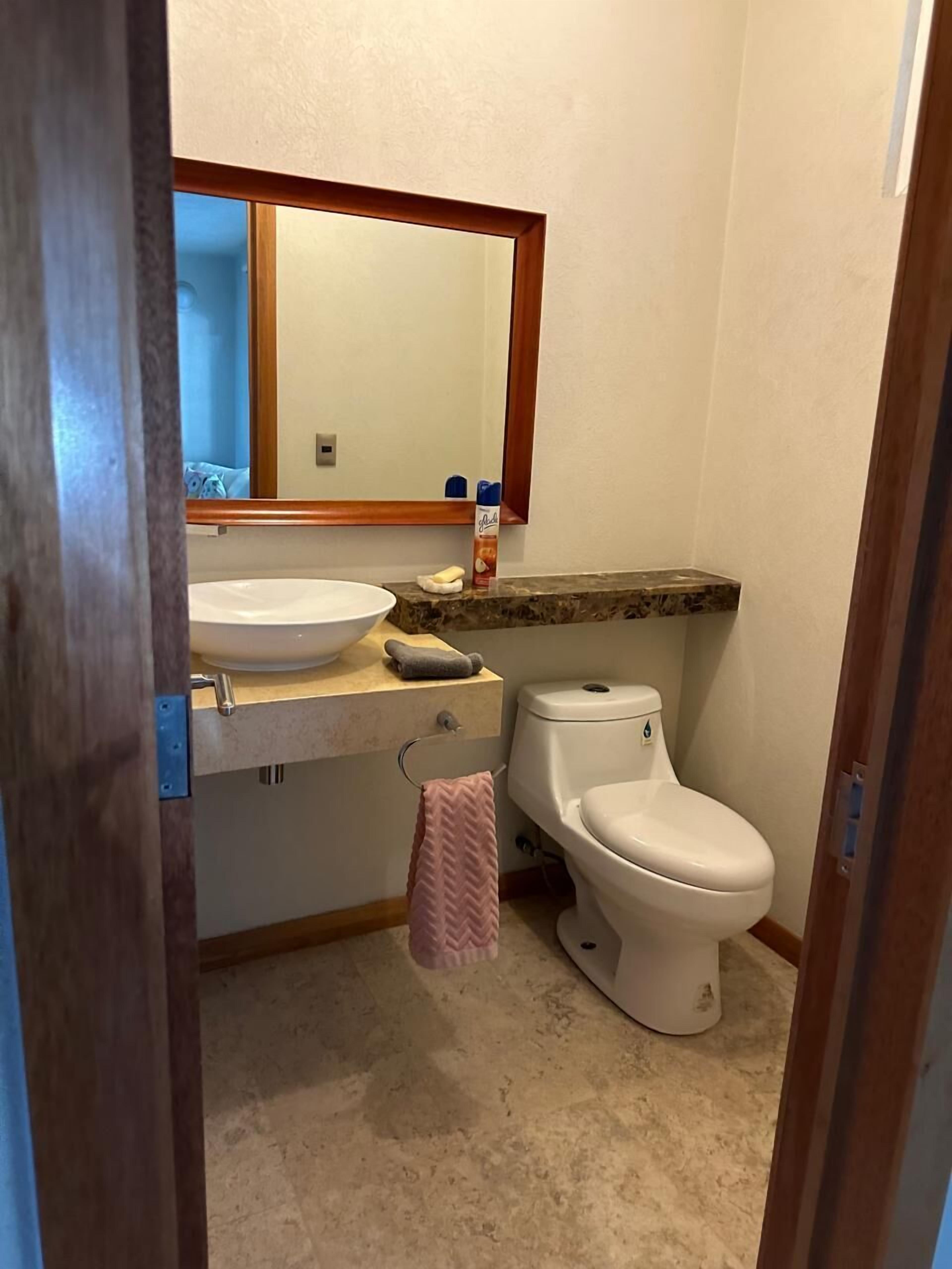 A bathroom with a sink, mirror, toilet, and a towel hanging on the wall.