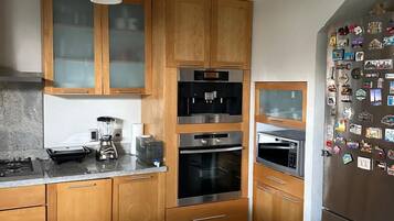 Una cocina moderna con armarios de madera, horno empotrado, microondas y refrigerador decorado con imanes.