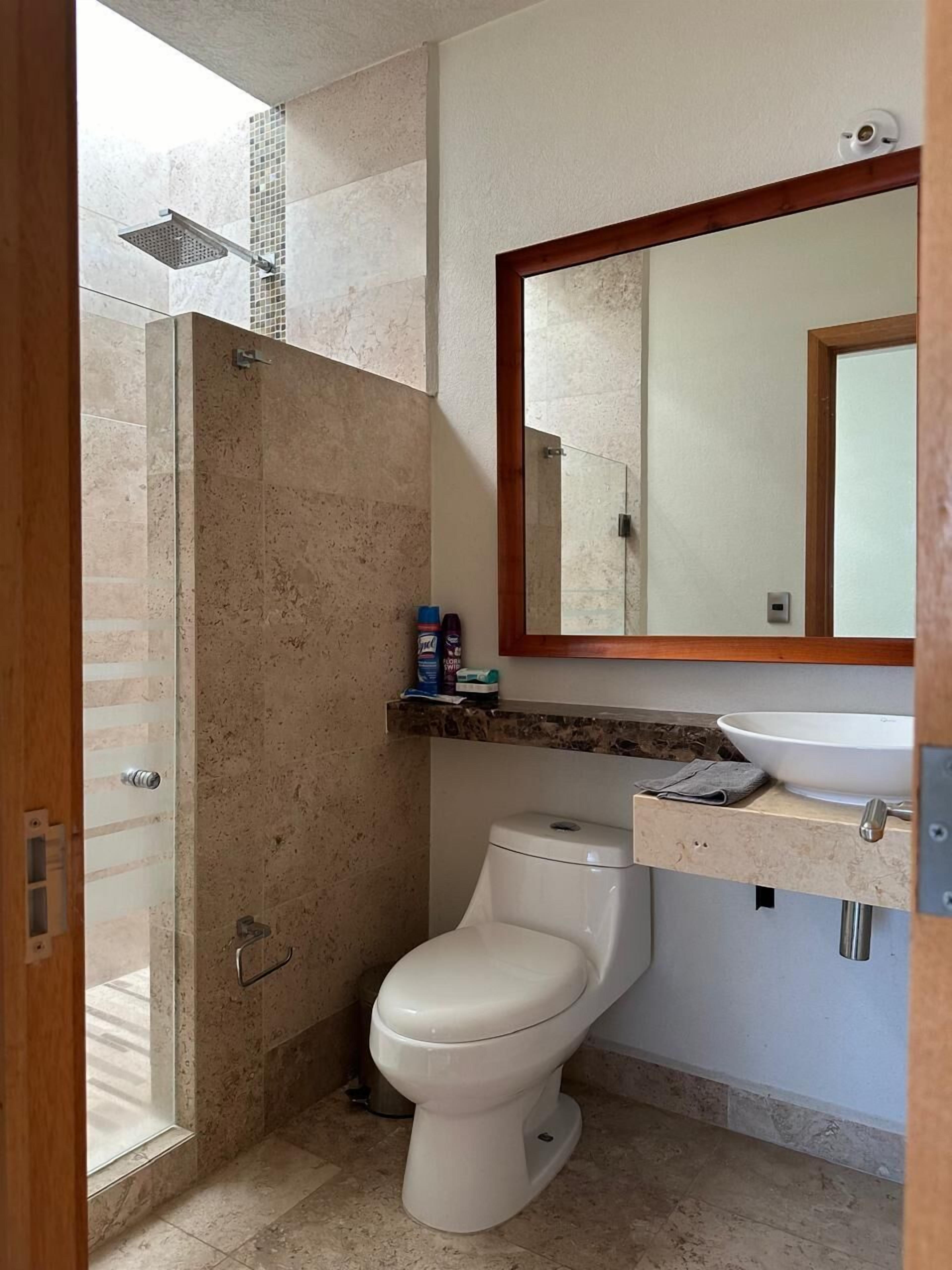 Un baño con ducha, inodoro, lavabo y un espejo sobre el lavabo.