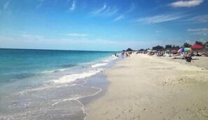 A beach with clear blue water and a sandy shore. There are umbrellas and people on the beach. - FANTASTIC!! LUXURY REMODEL, SUN FILLED-HEATED POOL, NEW LISTING, 5MIN 2FISHVILL (Punta Gorda)