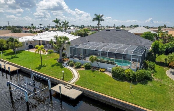 A house with a large glass greenhouse, a swimming pool, and a dock extending into a body of water. - FANTASTIC!! LUXURY REMODEL, SUN FILLED-HEATED POOL, NEW LISTING, 5MIN 2FISHVILL (Punta Gorda)
