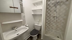 Een badkamer met een wit wastafel, toilet en douchecabine.
