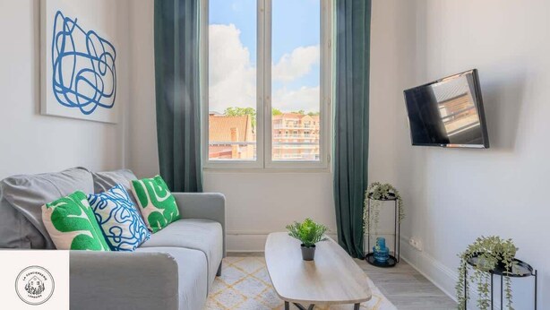 A modern living room with a sofa, a coffee table, and a TV mounted on the wall. - Le duplex inverse, Bollaert, Fac, gare, 2pers (Lens)