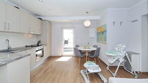 A modern kitchen with white cabinets, a marble countertop, and a dining area with a table and chairs. - Stunning home in Bast (Bast)