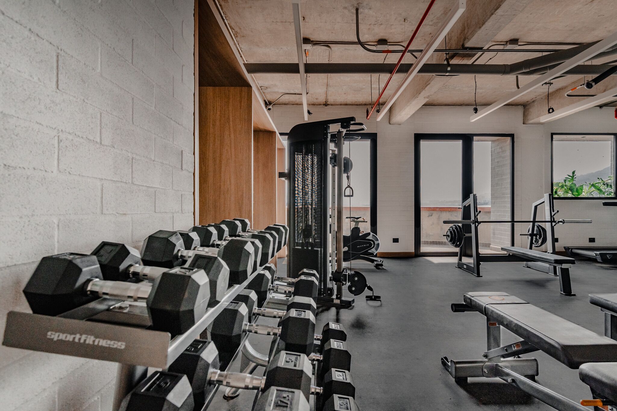 A gym with rows of dumbbells, a squat rack, and cardio equipment.