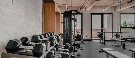 Un gimnasio con filas de mancuernas, una jaula de sentadillas y equipo cardiovascular.