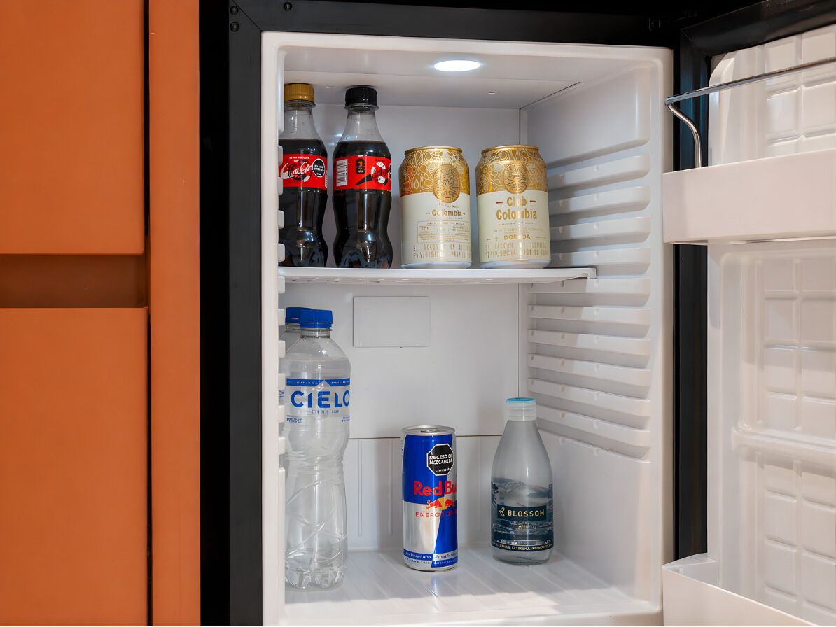 Un réfrigérateur contenant des boissons, notamment du Coca-Cola, du Red Bull et de l’eau Cielo.