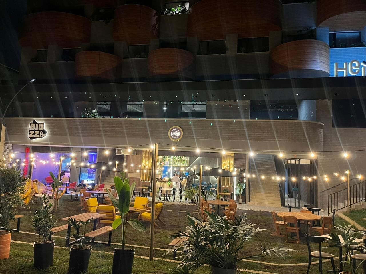 An outdoor seating area with tables and chairs, a bar area, and a staircase leading to an upper level.
