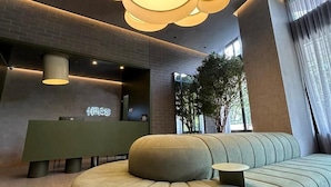 A modern reception area with a green sofa, a reception desk, and a large, circular ceiling light fixture. - Heiss Hotel By Jalo (Medellín)