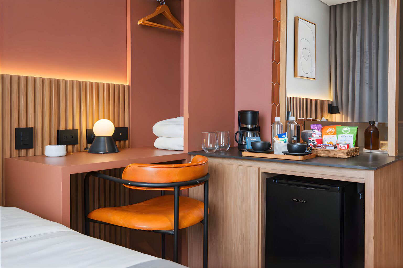 A hotel room with a bed, a desk with a lamp, a coffee maker, and a dishwasher.