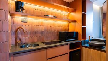 Una cocina moderna con cafetera, microondas, pileta y muebles de madera.