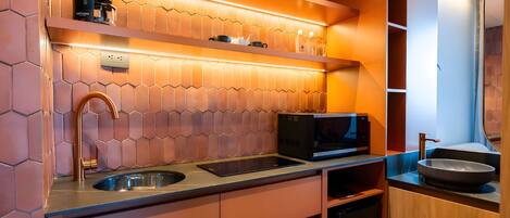 A modern kitchen with a coffee machine, microwave, sink, and wooden cabinets.