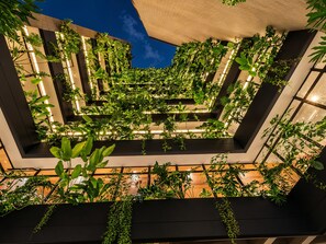 A multi-level atrium with a central garden feature surrounded by dark walls and wooden flooring. - Heiss Hotel By Jalo (Medellín)