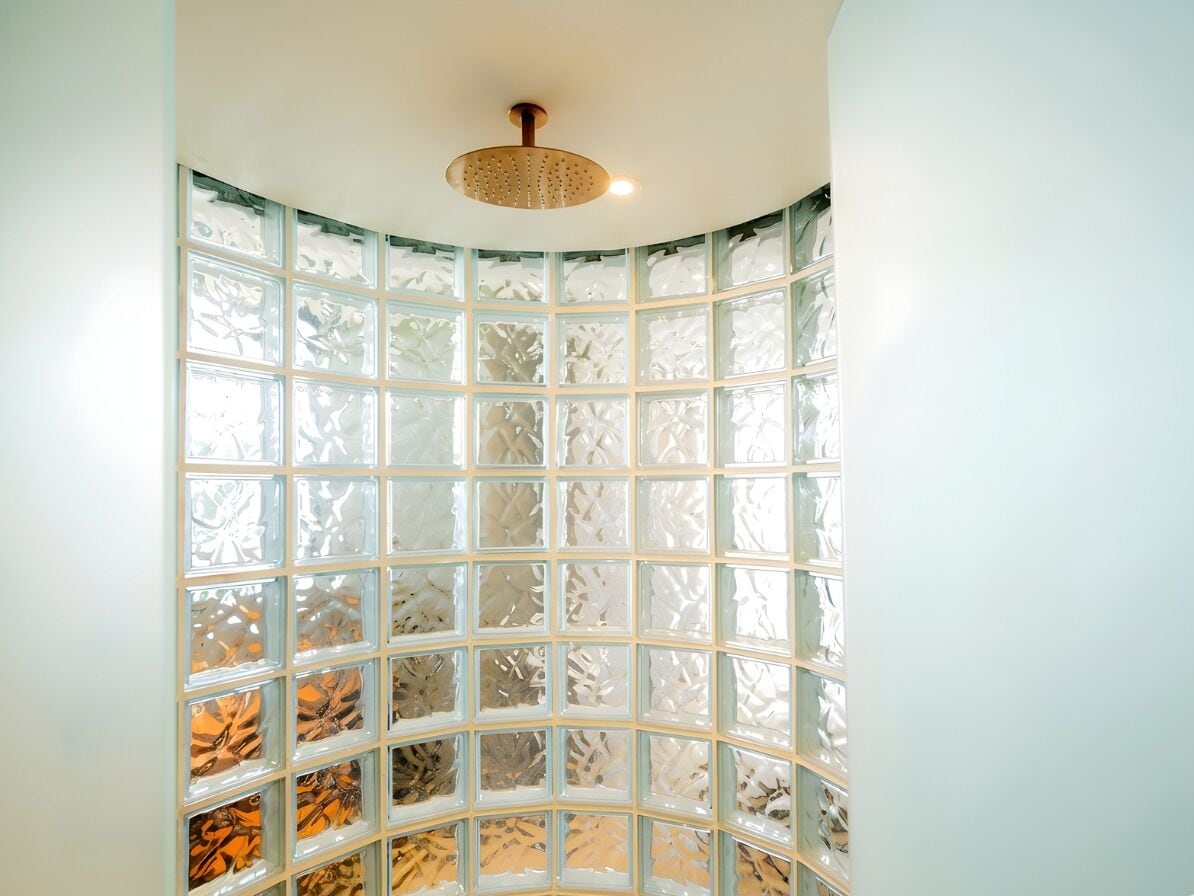 A room with a curved glass partition, a ceiling light fixture, and a view through the glass.