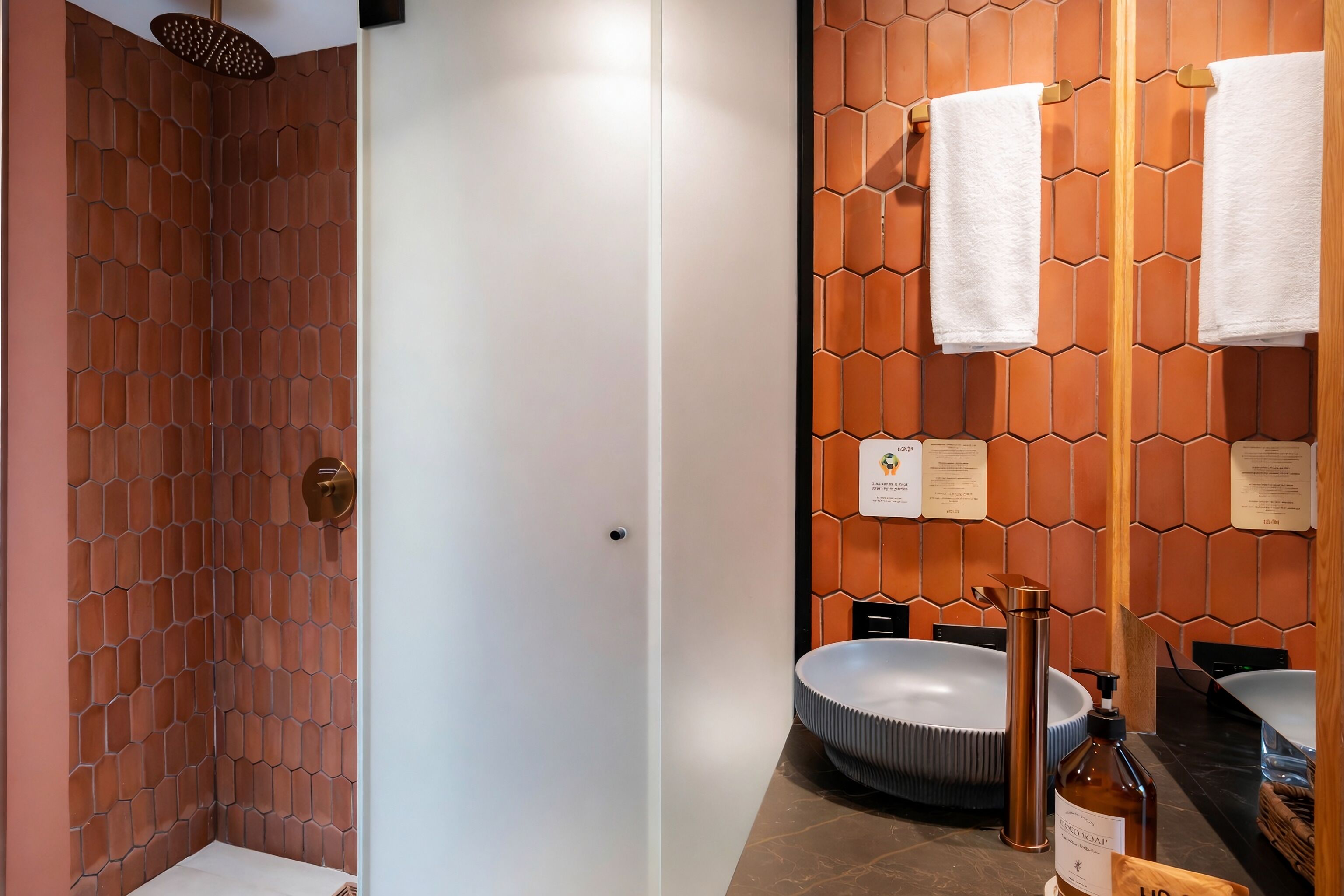 A modern bathroom with a shower, two sinks, and a mirror with towels.