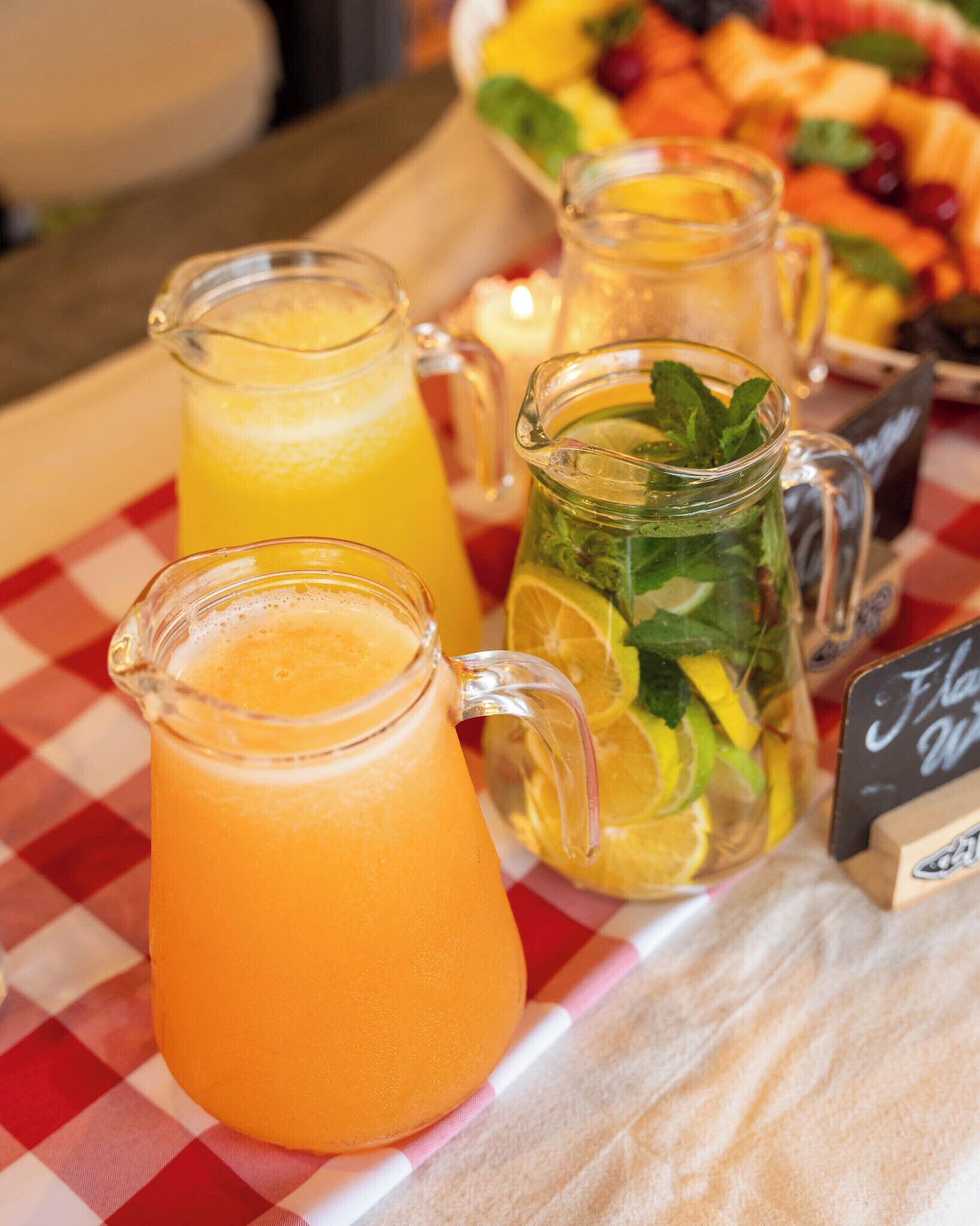 Une table avec deux carafes de jus d’orange et une carafe décorée de feuilles de menthe.