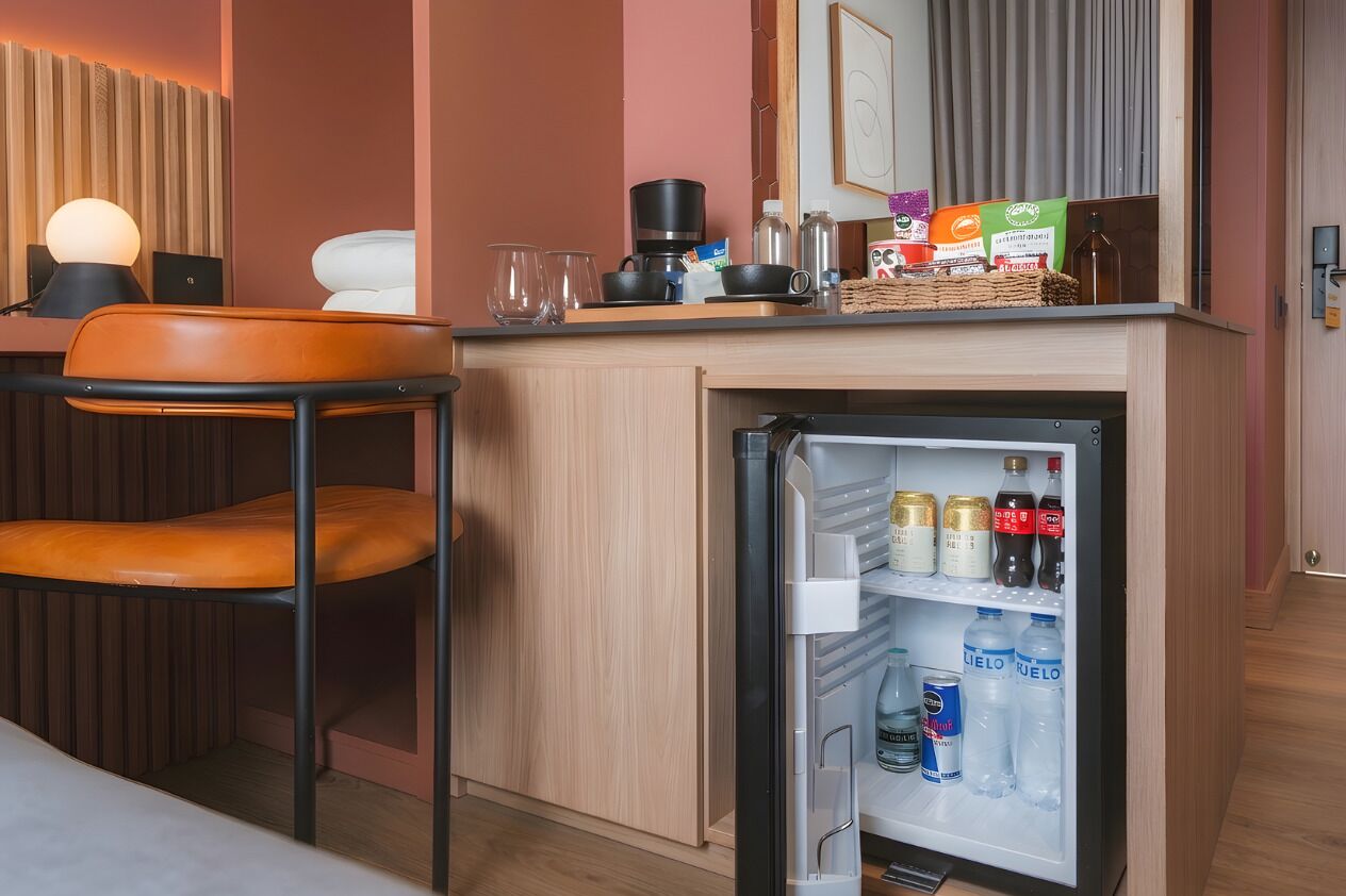 Et lille tekøkken med køleskab, kaffemaskine og forskellige spiser.