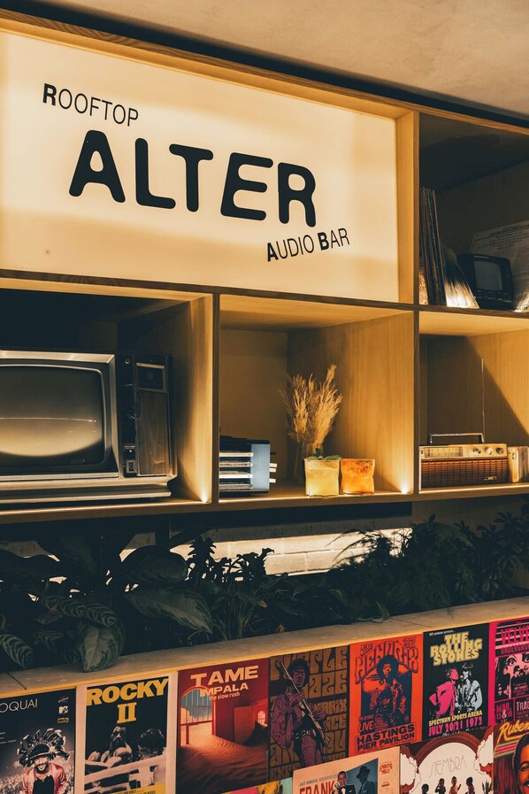 A room with a sign reading "ROOFTOP ALTER AUDIO BAR" and a shelf with various items including a vintage radio and decorative plants. - Heiss Hotel By Jalo (Medellín)