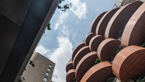 A modern building with a unique circular wooden balcony design, surrounded by greenery and a clear sky. - Heiss Hotel By Jalo (Medellín)