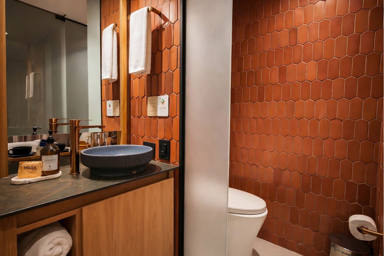 A modern bathroom with a wooden vanity, a round sink, and a toilet.