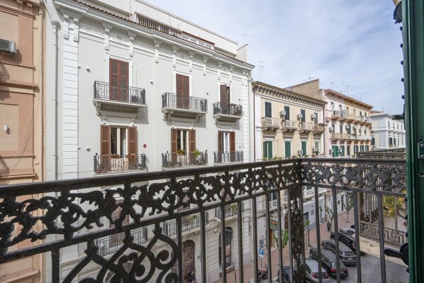 Un hilera de edificios con balcones, vista de la calle y automóviles estacionados.
