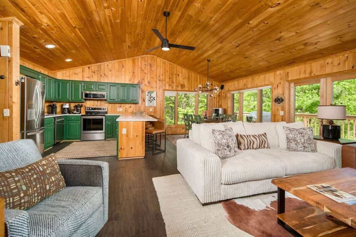 A wooden cabin interior with a kitchen, dining area, and living room.