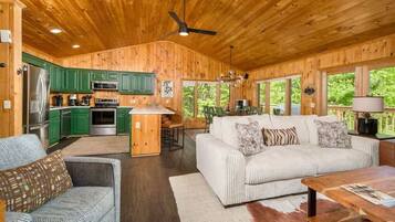 A wooden cabin interior with a kitchen, dining area, and living room.