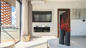 Una sala de estar moderna con un televisor grande, una mesa de comedor y dos jarrones altos con flores rojas.