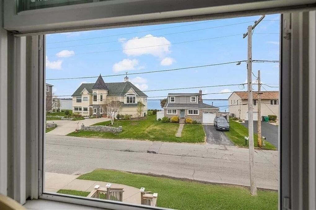 A residential street with houses, a car, and a clear sky.