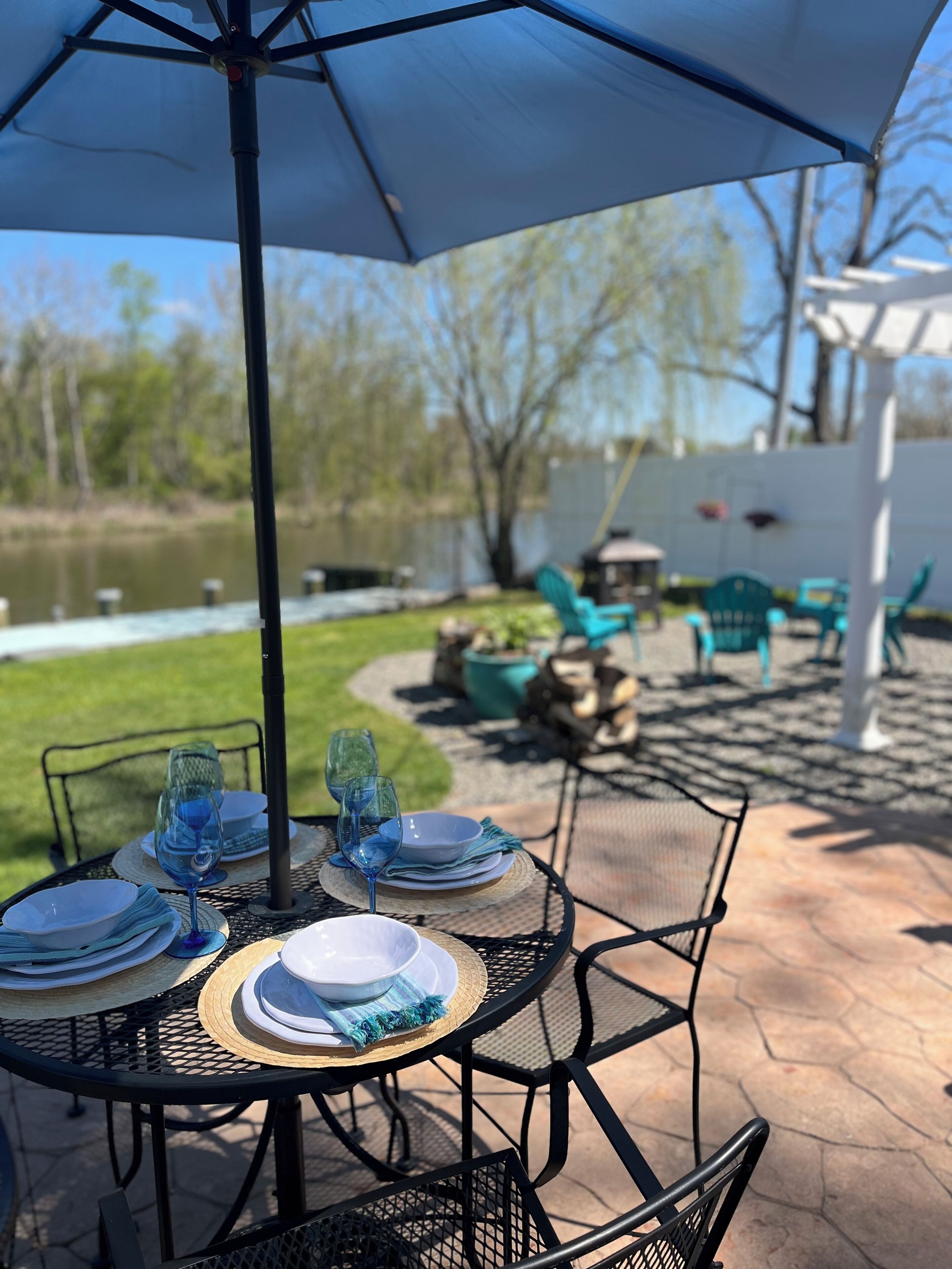 Un patio al aire libre con mesas redondas, sillas y un paraguas grande.