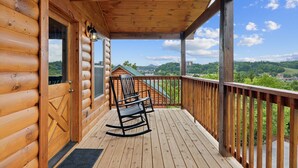 A wooden cabin with a porch, a rocking chair, and a view of the surrounding landscape. - Amazing Grace - Newly Built - 3 BR - Less Than 2 Miles from The Island (Pigeon Forge)