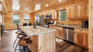 A spacious kitchen with wooden cabinets, granite countertops, and stainless steel appliances. - Amazing Grace - Newly Built - 3 BR - Less Than 2 Miles from The Island (Pigeon Forge)