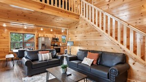 A cozy log cabin interior with a living room, dining area, kitchen, and a staircase. - Amazing Grace - Newly Built - 3 BR - Less Than 2 Miles from The Island (Pigeon Forge)