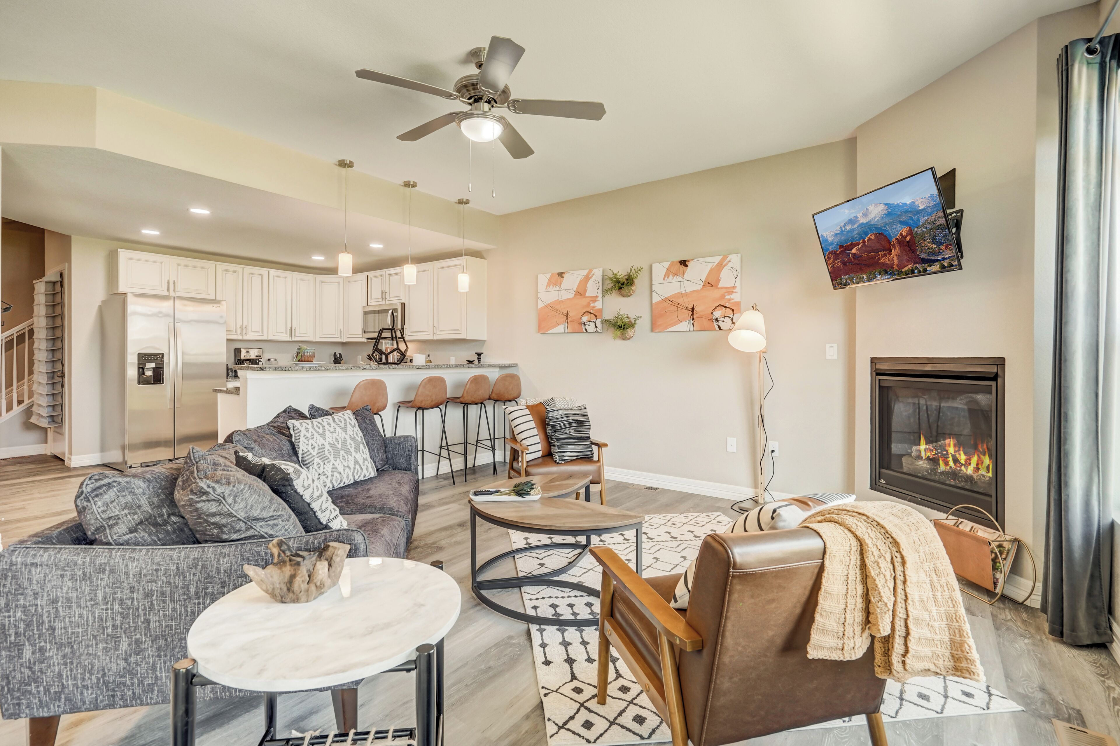 A modern living room with a fireplace, a dining area, and a kitchen in the background.