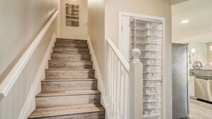 A staircase with wooden steps and white railings leading to a room with a kitchen area. - Mid-Brambleberry (Colorado Springs)