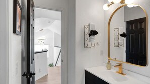 A bathroom with a white vanity, a large mirror with gold accents, and a black door. - Colorful Colorado house by DIA Airport Rockies & Downtown! (Commerce City)