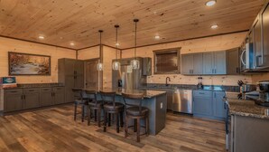 A modern kitchen with wooden floors, grey cabinets, and stainless steel appliances. - Mountain Dreams - Mountain views for miles! (Sevierville)