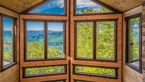 A cabin with a large, triangular roof and multiple windows offering expansive views of a forested mountain landscape. - Mountain Dreams - Mountain views for miles! (Sevierville)