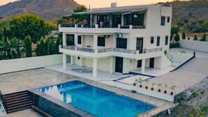 A modern two-story house with a swimming pool, surrounded by greenery and a mountain in the background. - The Udaisagar Retreat - Udaipur (Udaipur)