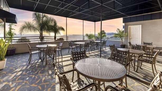 A covered outdoor seating area with tables and chairs, overlooking a body of water. - Hilton Vacation Club Riviera Beach & Shores (Dana Point)
