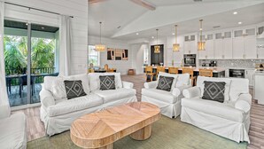 A modern living room with white sofas, a wooden coffee table, and pendant lighting.