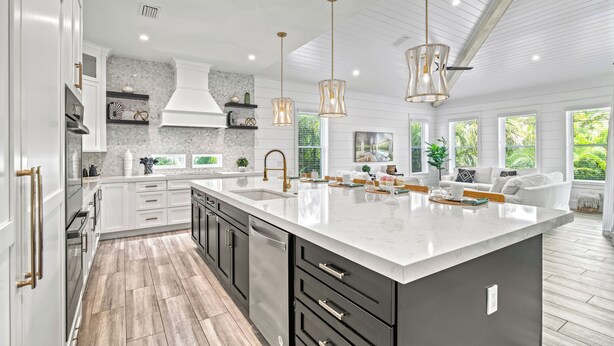 A spacious kitchen with a large island, white cabinetry, and pendant lighting.