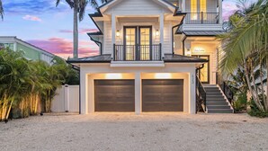 A two-story house with a balcony, two garage doors, and a staircase leading to the upper level.