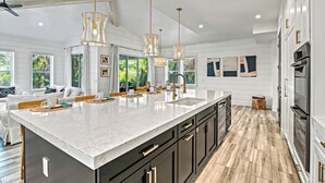 A spacious kitchen with a large island, modern pendant lights, and a view of the outdoors.