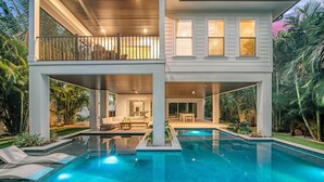 A two-story house with a swimming pool, outdoor furniture, and a balcony.