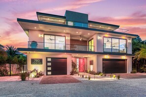 Ein modernes, zweistöckiges Haus mit großer Garage, Balkon und gut erhelltem Eingang.